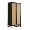 Angled view of the black rattan 2-door wardrobe with woven cane doors against a dark grey textured wall.