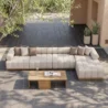Brown wicker modular sofa on a paved patio with greenery.