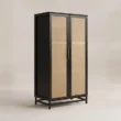 Angled view of black cane-front wardrobe with brass-tone handles
