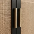 Close-up of brass-tone handles against black frames and woven cane doors