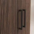 Close-up of black handles against the vertical fluted wood finish