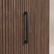 Close-up of matte-black handle on the walnut fluted door front