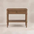 Aldren wooden bedside table with single drawer, open shelf, warm brown finish, and turned legs.