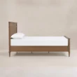 Side view of Aldren wooden bed with paneled frame, turned legs, and warm brown finish.