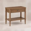 Angled view of Aldren wooden bedside table with single drawer, open shelf, turned legs, and warm brown finish.