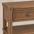 Close-up of Aldren wooden bedside table showing framed drawer, carved detailing, metal knob, and warm brown finish.