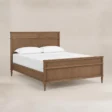 Aldren wooden bed in Pakistan, angled view with warm brown finish, panel headboard and matching footboard.