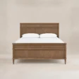 Aldren Wooden Bed in warm brown wood finish with panel headboard and matching footboard, front view.