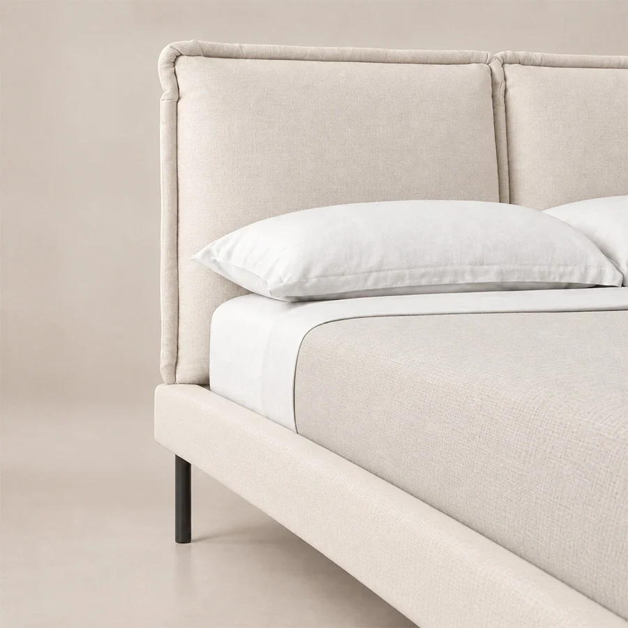 Amelia-upholstered-bed-closeup-view Close-up of Nolven Softline Upholstered Bed in warm ivory fabric showing the padded headboard and slim metal legs.