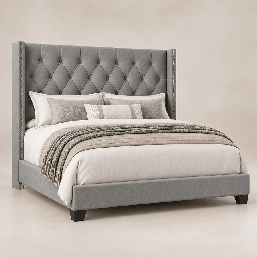 Angled view of Bellmere Wingback Bed in grey upholstery with diamond-tufted headboard and nailhead trim.