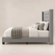 Side view of Bellmere Wingback Bed in grey upholstery with tufted headboard and nailhead trim.