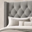 Close-up of Bellmere Wingback Bed in cool grey upholstery with diamond tufting and silver nailhead trim.