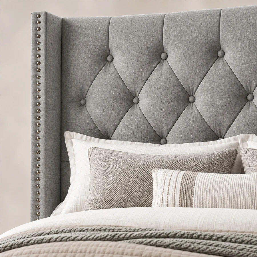 Close-up of Bellmere Wingback Bed in cool grey upholstery with diamond tufting and silver nailhead trim.