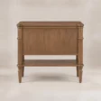Back view of Aldren wooden bedside table with open lower shelf, turned legs, and warm brown finish.