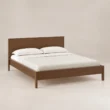 Angled view of Kelden Linea Bed in Walnut Brown finish with clean panel headboard and slim wooden legs.