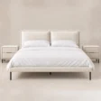 Nolven Softline Bed Set in warm ivory upholstery with matching two-drawer bedside tables, front view.