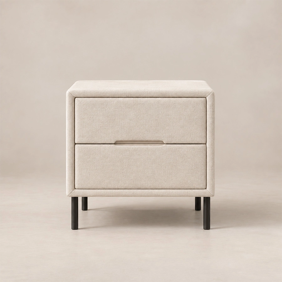 Nolven Softline matching two-drawer bedside table in warm ivory upholstery with slim black metal legs.
