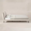 Side view of Nolven Softline Upholstered Bed in warm ivory fabric with padded headboard and slim metal legs.