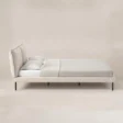 Side view of Nolven Softline Upholstered Bed in warm ivory fabric with padded headboard and slim metal legs.