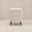 Side view of Nolven Softline matching bedside table in warm ivory upholstery with slim black metal legs.