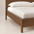 Close-up of Kelden Linea Bed in Walnut Brown finish showing the wooden frame, side rail, and slim tapered leg.